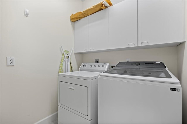 laundry area with baseboards, cabinet space, and washer and clothes dryer