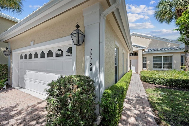view of side of home with an attached garage, stucco siding, and driveway