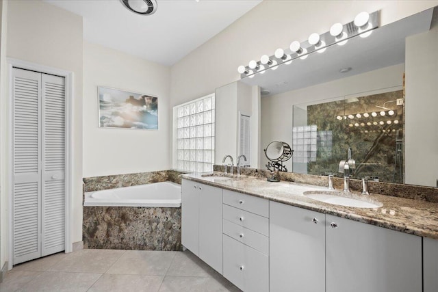 full bath with a closet, a garden tub, tile patterned flooring, double vanity, and a sink