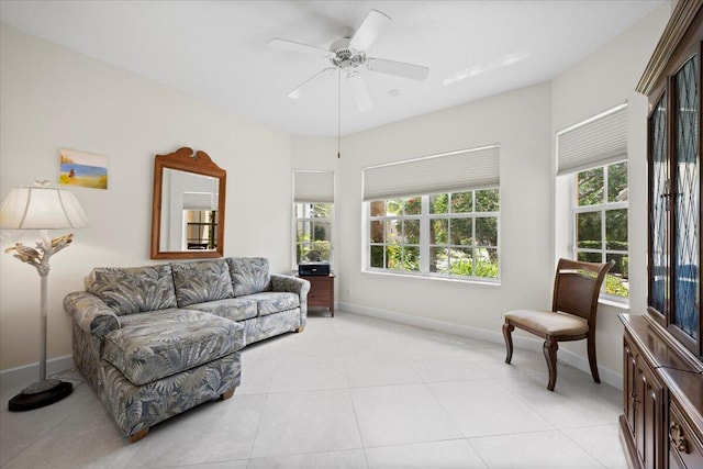 living area featuring a ceiling fan, baseboards, and light tile patterned floors