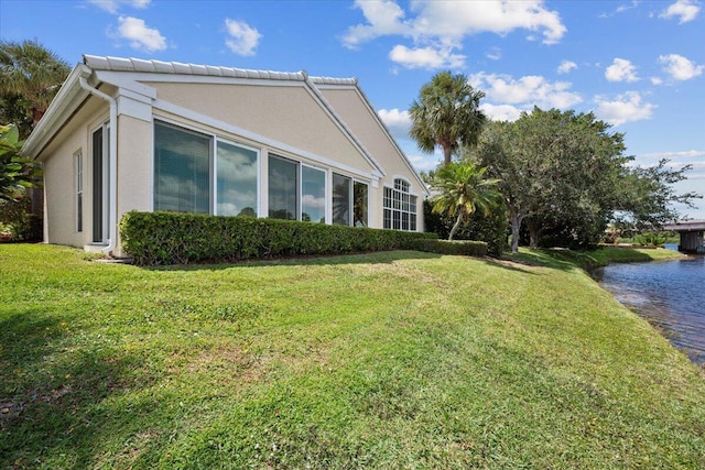 view of property exterior with a lawn, a water view, and stucco siding