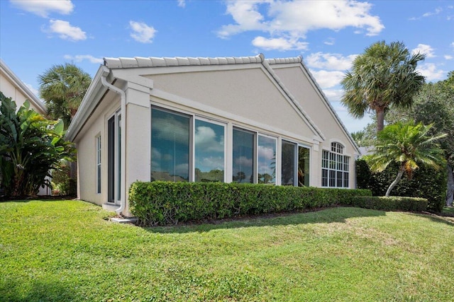 view of side of home with a lawn and stucco siding
