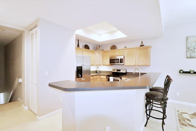 10520 SW Stephanie Way Unit 2204, Port Saint Lucie, FL 34987 - kitchen with a breakfast bar, light brown cabinets, stainless steel appliances, baseboards, and a peninsula