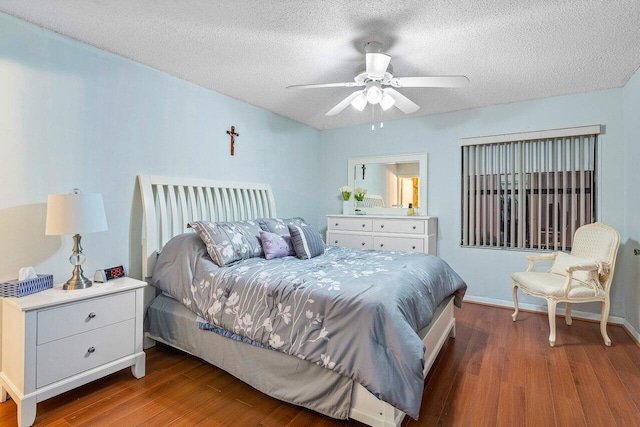 bedroom with a textured ceiling, wood finished floors, a ceiling fan, and baseboards