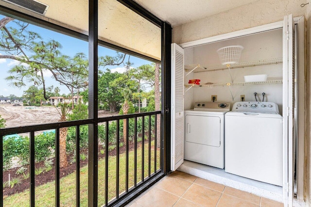 washroom with light tile patterned floors, washing machine and clothes dryer, and laundry area