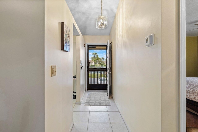 doorway featuring baseboards, light tile patterned floors, and an inviting chandelier