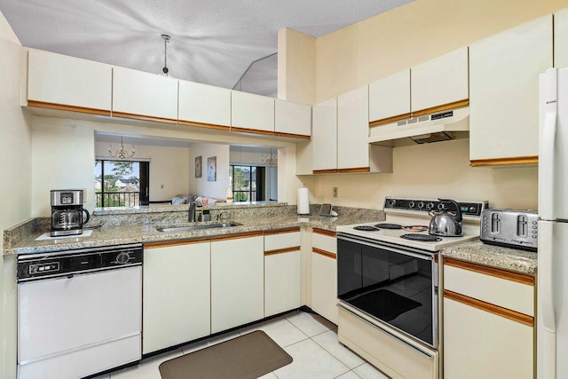 kitchen featuring white appliances, under cabinet range hood, light countertops, and a sink