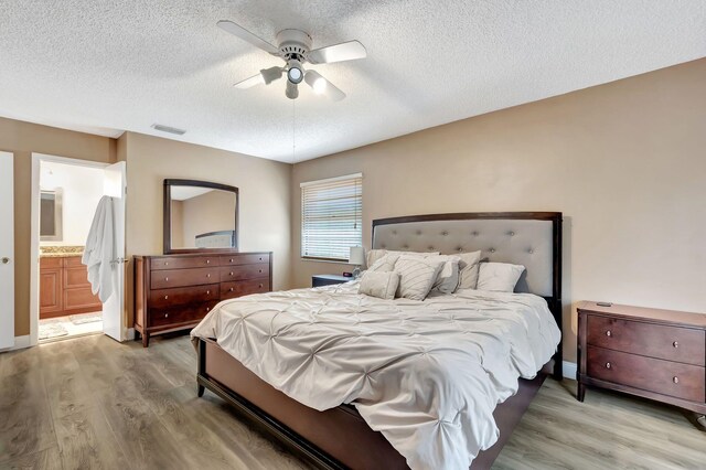 bedroom featuring light wood finished floors, a textured ceiling, and visible vents