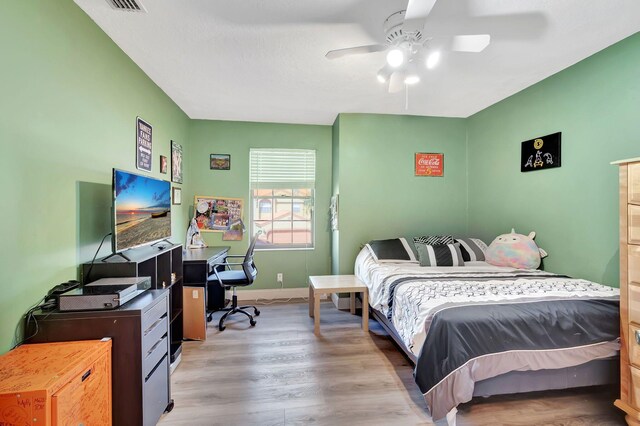 bedroom with a ceiling fan, baseboards, visible vents, and wood finished floors