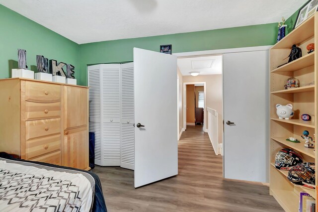 bedroom with a closet, baseboards, attic access, and wood finished floors