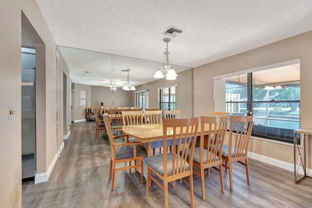 dining room with baseboards, a textured ceiling, light wood-style flooring, and visible vents