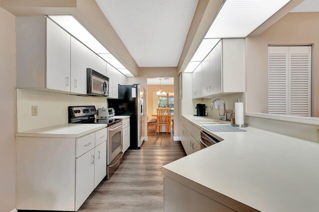 kitchen featuring white cabinetry, a sink, light countertops, stainless steel appliances, and light wood-style flooring