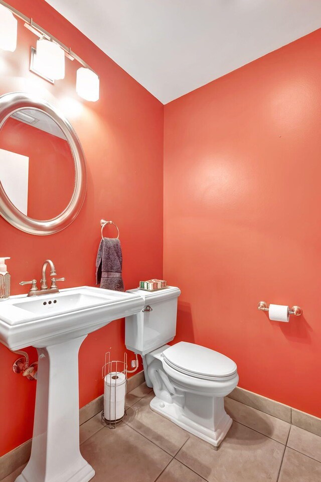 half bath featuring tile patterned flooring, baseboards, and toilet