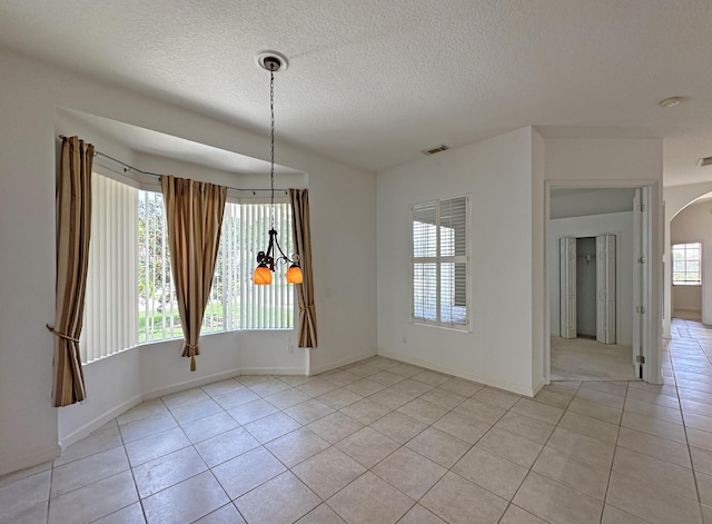 573 SW Saint Kitts St, Port Saint Lucie, FL 34953 - unfurnished dining area with arched walkways, light tile patterned floors, and a textured ceiling