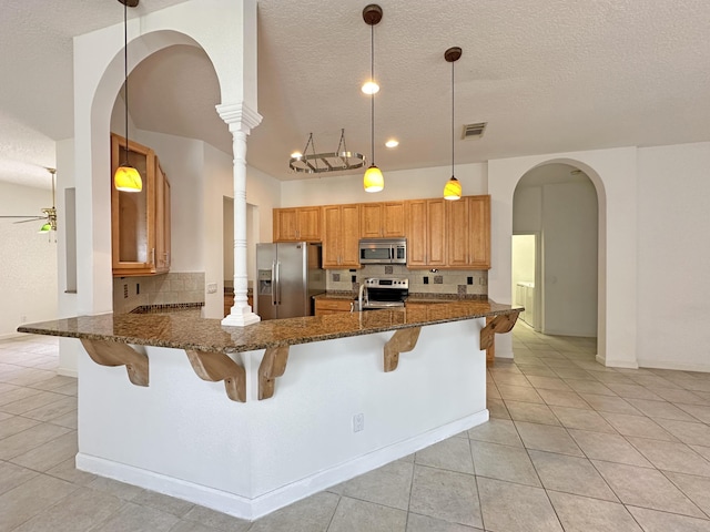 573 SW Saint Kitts St, Port Saint Lucie, FL 34953 - kitchen with appliances with stainless steel finishes, arched walkways, decorative backsplash, light tile patterned flooring, and a textured ceiling