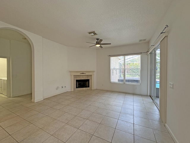 573 SW Saint Kitts St, Port Saint Lucie, FL 34953 - unfurnished living room featuring ceiling fan, a textured ceiling, light tile patterned floors, a fireplace, and arched walkways