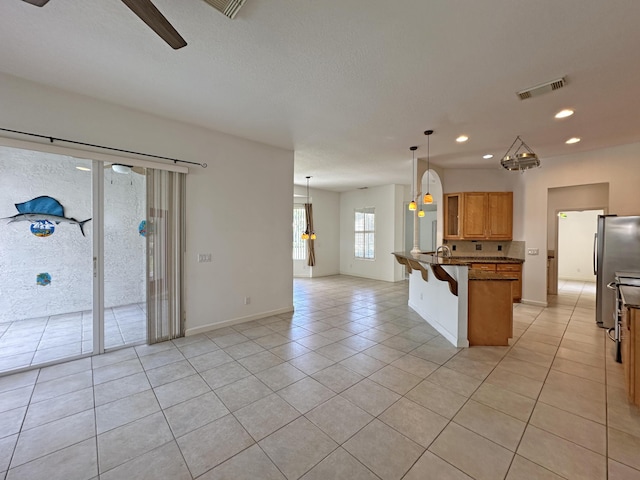 573 SW Saint Kitts St, Port Saint Lucie, FL 34953 - kitchen featuring open floor plan, light tile patterned floors, freestanding refrigerator, a breakfast bar area, and recessed lighting