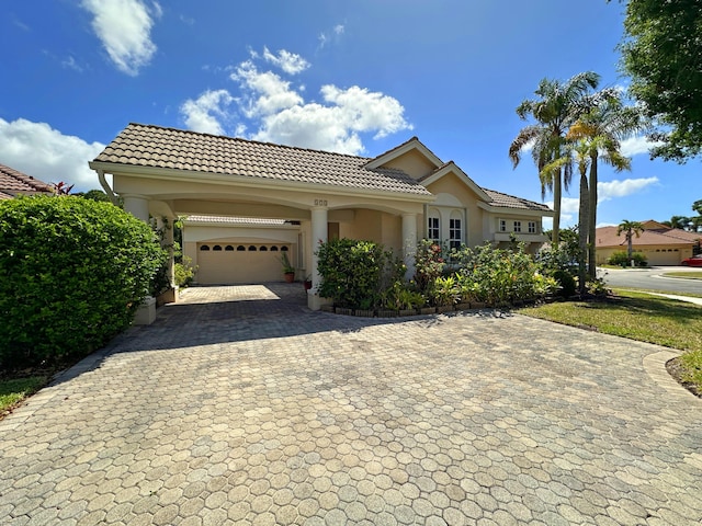 573 SW Saint Kitts St, Port Saint Lucie, FL 34953 - mediterranean / spanish-style home featuring decorative driveway, a tiled roof, stucco siding, and an attached garage