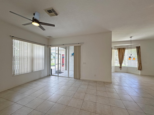 573 SW Saint Kitts St, Port Saint Lucie, FL 34953 - empty room featuring a ceiling fan, light tile patterned flooring, a textured ceiling, and a chandelier