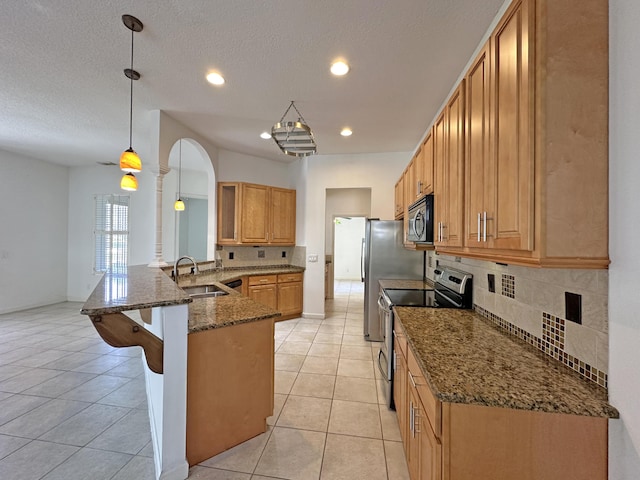 573 SW Saint Kitts St, Port Saint Lucie, FL 34953 - kitchen with stainless steel electric stove, a kitchen bar, tasteful backsplash, a peninsula, and dark stone counters