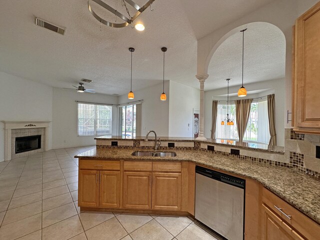 573 SW Saint Kitts St, Port Saint Lucie, FL 34953 - kitchen featuring stainless steel dishwasher, a textured ceiling, a ceiling fan, healthy amount of natural light, and a tiled fireplace