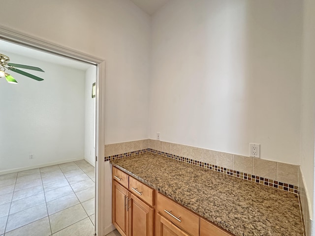 573 SW Saint Kitts St, Port Saint Lucie, FL 34953 - kitchen with dark stone counters, a ceiling fan, light tile patterned floors, and brown cabinetry