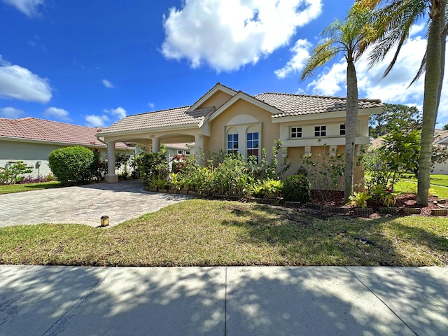 573 SW Saint Kitts St, Port Saint Lucie, FL 34953 - mediterranean / spanish-style home featuring a tile roof, a front lawn, and stucco siding