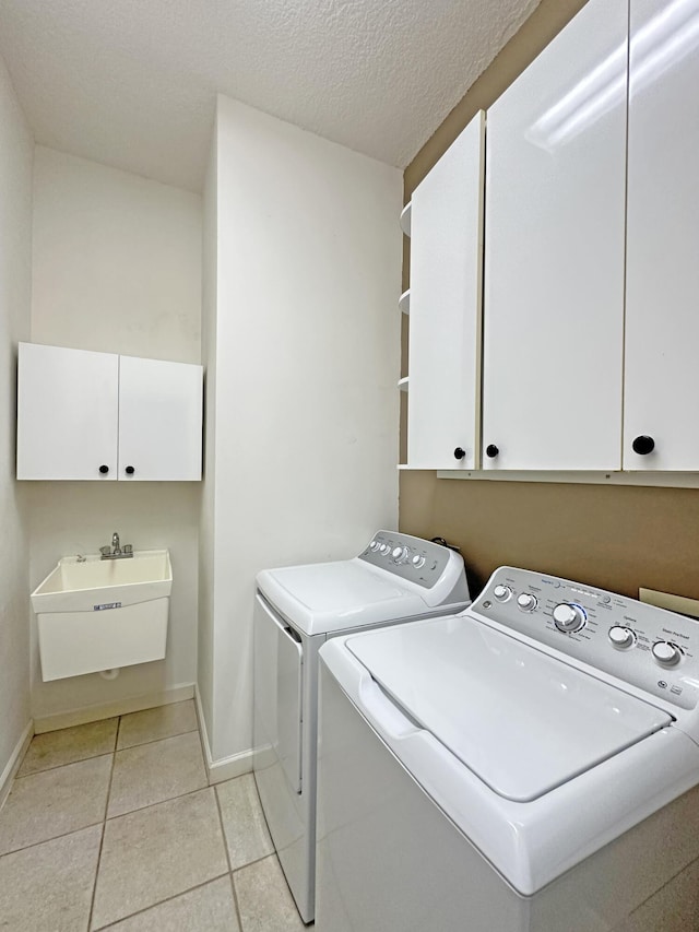 573 SW Saint Kitts St, Port Saint Lucie, FL 34953 - laundry area with cabinet space, washer and clothes dryer, light tile patterned floors, and a textured ceiling