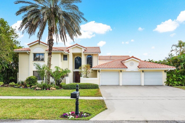 mediterranean / spanish-style house with stucco siding, driveway, a front yard, and a garage