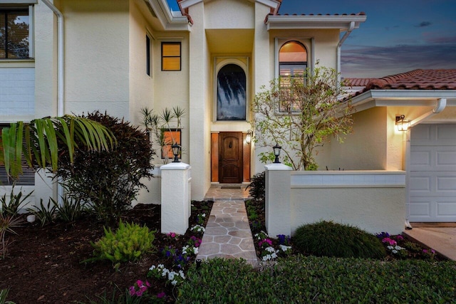 property entrance featuring a garage, stucco siding, and a tiled roof