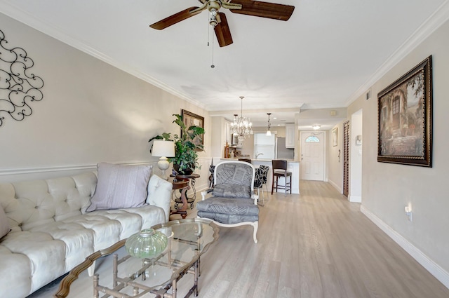 living room with a ceiling fan, light wood-style flooring, ornamental molding, a chandelier, and baseboards