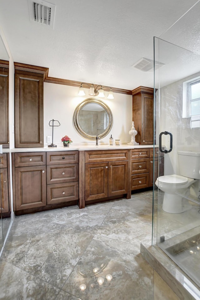 bathroom with toilet, vanity, a shower stall, and a textured ceiling