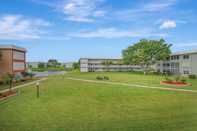 surrounding community with a water view and a yard