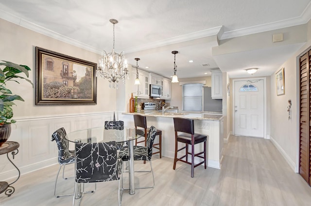 dining space with light wood-style floors, ornamental molding, and a chandelier