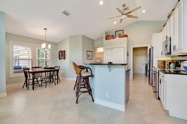 kitchen featuring white cabinets, dark countertops, a breakfast bar area, ceiling fan with notable chandelier, and stainless steel appliances