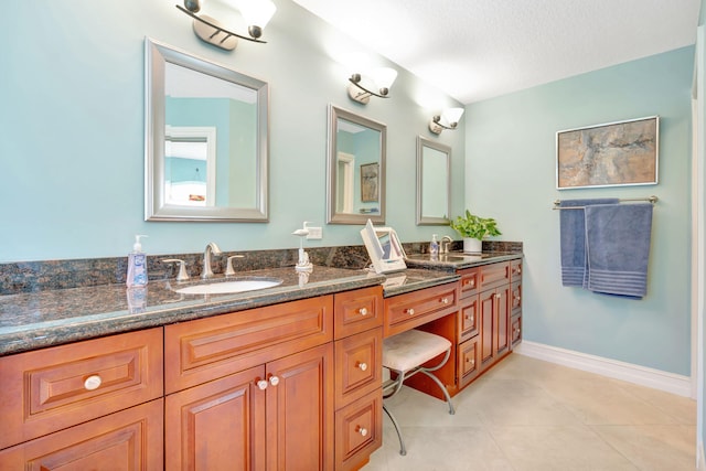 full bathroom featuring tile patterned flooring, double vanity, baseboards, a textured ceiling, and a sink