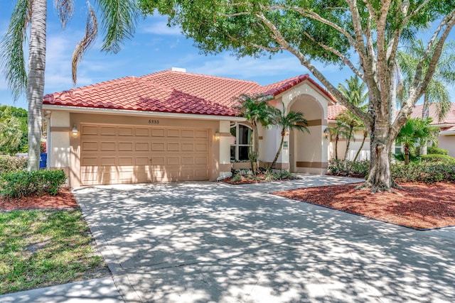 mediterranean / spanish home featuring concrete driveway, a tiled roof, an attached garage, and stucco siding