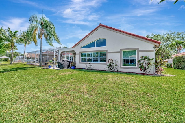 back of property featuring glass enclosure, stucco siding, a yard, and a tile roof