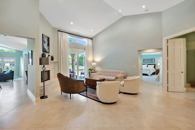 living room featuring a fireplace with raised hearth, high vaulted ceiling, recessed lighting, baseboards, and light tile patterned floors