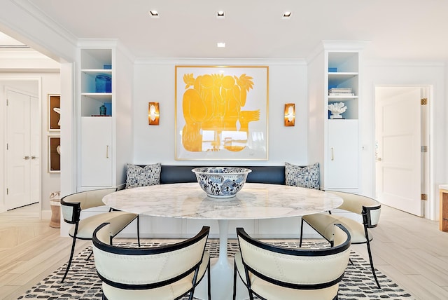 dining room featuring breakfast area, built in shelves, ornamental molding, and light wood finished floors