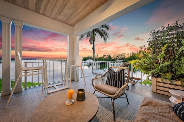 patio terrace at dusk with a balcony and a water view