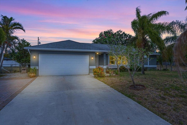 ranch-style house with a garage, stucco siding, driveway, and fence