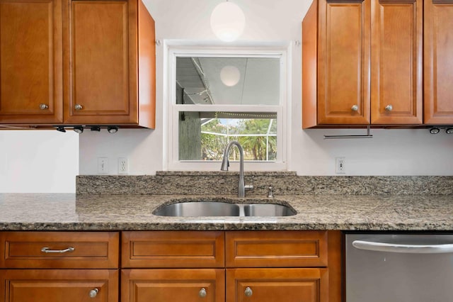 kitchen with a sink, stone counters, dishwasher, and brown cabinets
