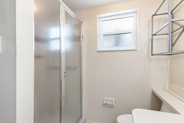 bathroom with baseboards, a stall shower, and toilet