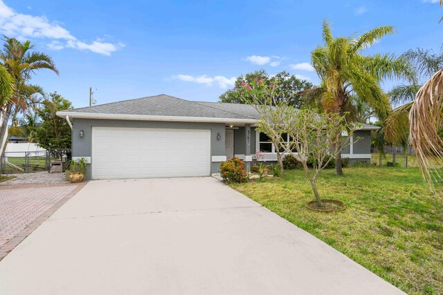 ranch-style home with fence, a garage, stucco siding, a front yard, and driveway