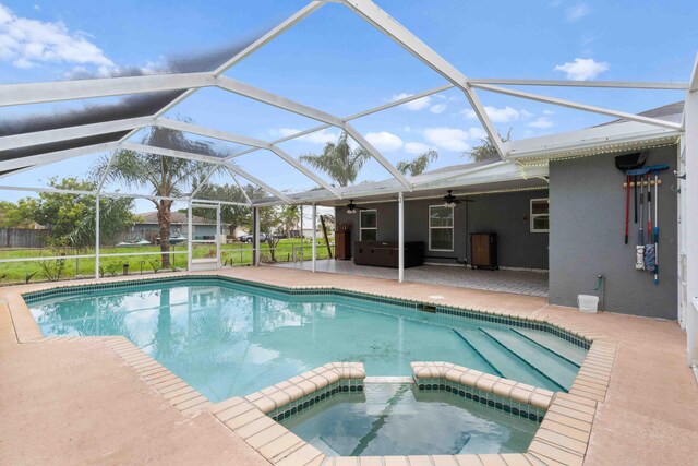 view of swimming pool featuring a lanai, ceiling fan, a pool with connected hot tub, and a patio area