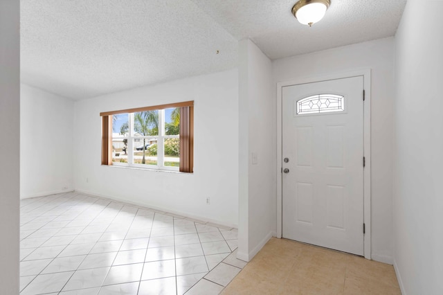 foyer featuring baseboards, a textured ceiling, and light tile patterned flooring