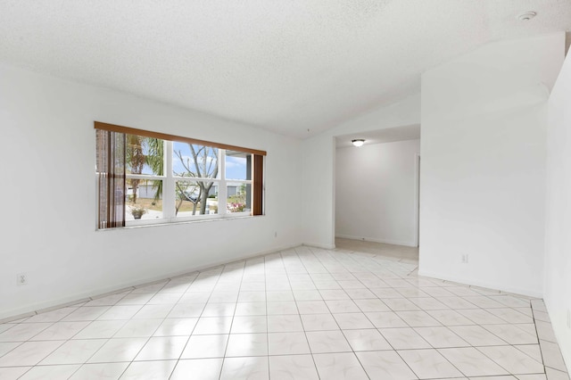 empty room with baseboards, vaulted ceiling, and a textured ceiling