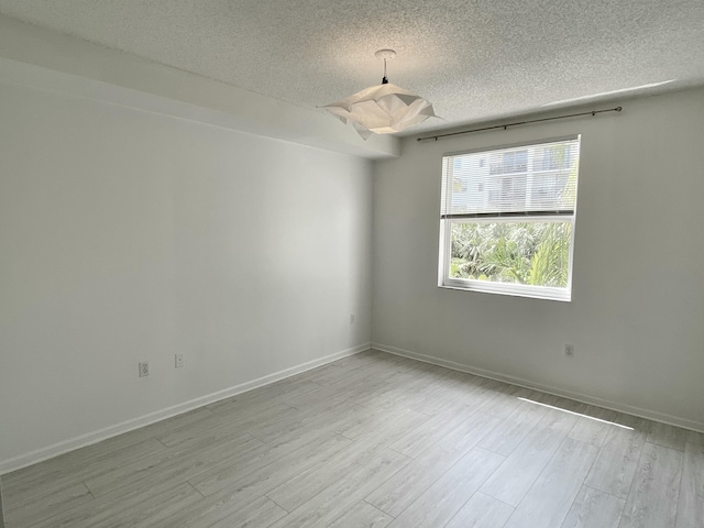 empty room featuring baseboards, a textured ceiling, and wood finished floors