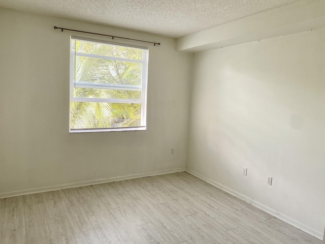 unfurnished room featuring baseboards, a textured ceiling, plenty of natural light, and light wood-style flooring
